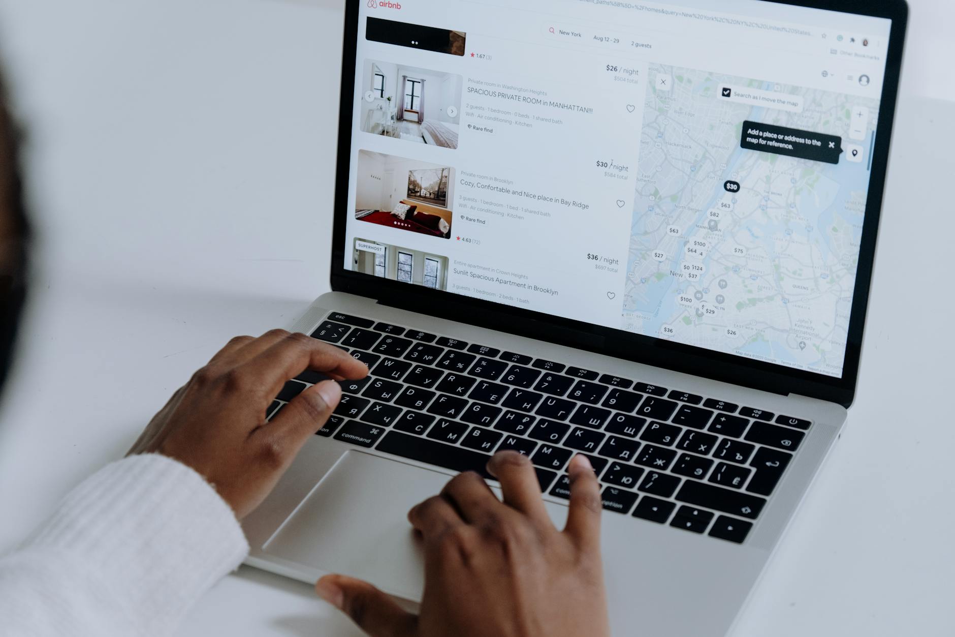 person using macbook pro on white table